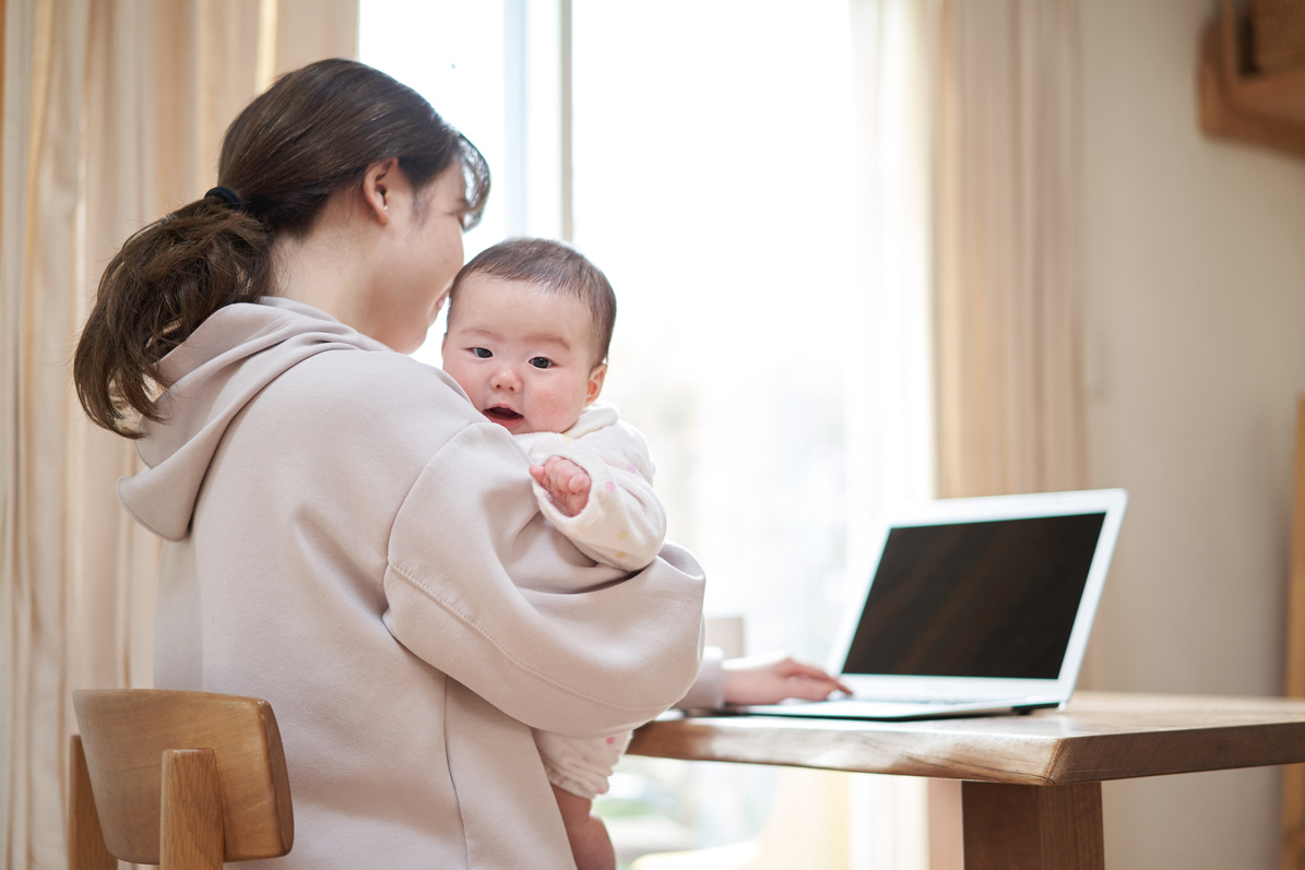 Asian mom working while babysitting her baby